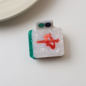 Close-up of Mahjong-style hair claw clip with green accents and red lucky character