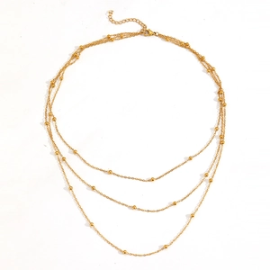 Detailed close-up of triple-layered gold titanium necklace with beads and lobster clasp