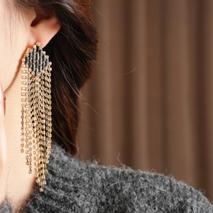 Macro detail of long tassel earrings with black crystals and sparkling rhinestone chains