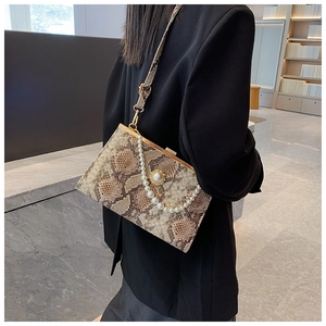 Détail du sac à main motif serpent avec poignée en perles et bordure dorée