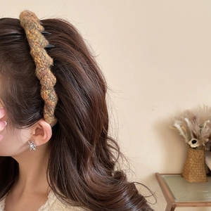 Detail showing the thick knitted wavy texture of the acrylic headband in mixed yellow tones