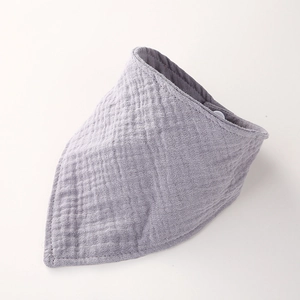 Gros plan du bavoir en mousseline de coton lilas montrant la texture douce et le bouton-pression