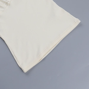 Gros plan détaillé sur la texture en maille et l'ourlet en dentelle du haut blanc cassé