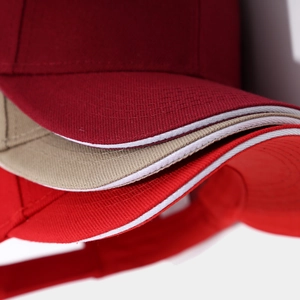 Detailed close-up of sandwich peak cotton baseball caps in burgundy, khaki and red colors