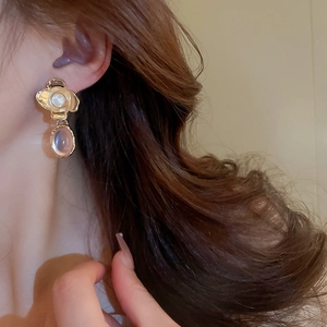 Detail of vintage flower earrings with metallic texture and oval resin gems on model