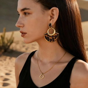Boucles d'oreilles léopard dorées en éventail et collier sur mannequin dans le désert