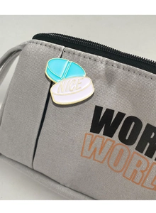 Close-up of enamel pill badge with NICE text on grey canvas bag decoration