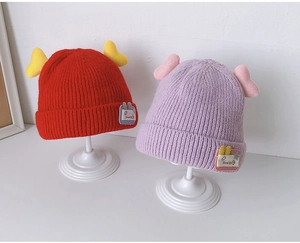Detail of red and purple knitted baby beanies with cute wings and ribbed texture