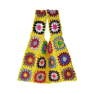 Detail of colorful hand-crocheted granny square patterns on a yellow cotton tote bag
