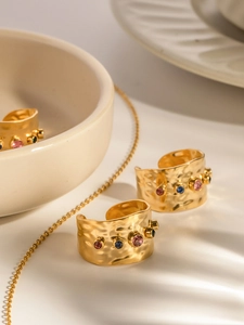 Detail eines breiten vergoldeten Zirkon-Rings mit bunten Edelsteinen auf Keramik
