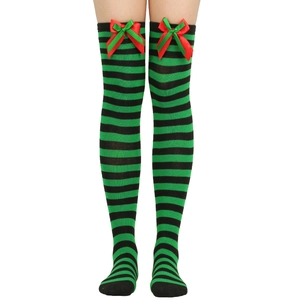 Detail of green and black striped over-knee Christmas socks with festive red ribbon bows