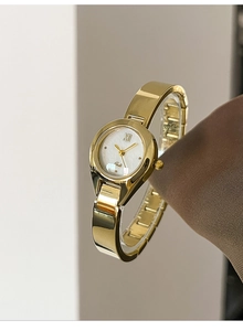 Detailed close-up of a women's gold watch with a mother-of-pearl dial and metal band