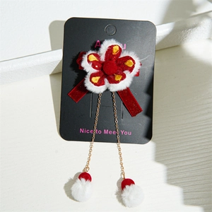 Detail of red floral velvet hair clip with long white fur ball tassels and gold chains