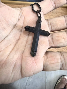 Gros plan d'un pendentif croix en acier inoxydable noir mat au design géométrique