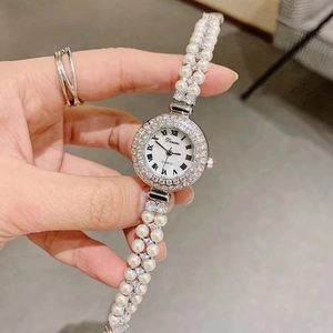 Detail of luxury women's watch with pearl bracelet, diamond bezel and white Roman dial