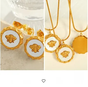 Dettaglio ravvicinato di orecchini e collana con api dorate e inserti in conchiglia