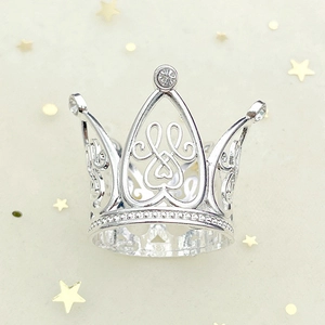Close-up of silver crown with hollow heart design and sparkling crystals on star background