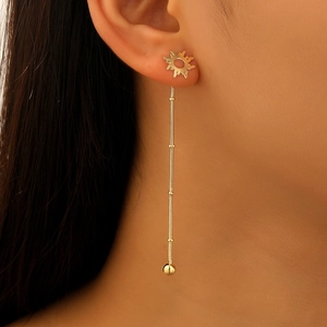 Detail view of long golden fringe earrings with sun design and metallic tassel