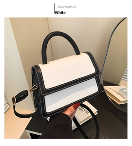 Detail view of contrast color handbag with fine white stitching on black edges