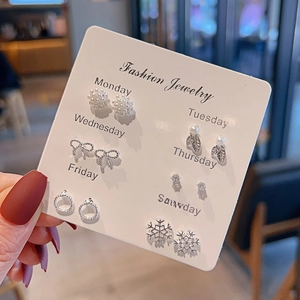 Detailed view of seven pairs of silver stud earrings displayed on a weekly organizer card