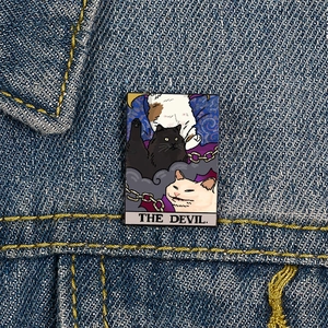 Funny Tarot The Devil Cat enamel pin accessory on a blue denim jacket pocket