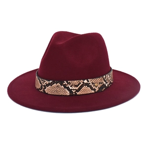 Gros plan d'un chapeau fedora rouge bordeaux avec ruban peau de serpent et rivet doré
