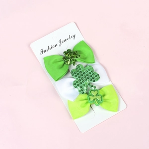Close-up of green and white ribbon bow hair clips with glitter shamrock detail on card