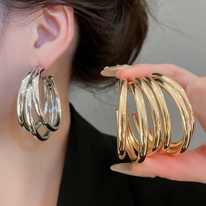 Detailed macro of silver and gold layered hoop earrings with high-gloss metallic finish