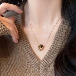 U-shaped gold stainless steel necklace with brown tiger eye stone on brown knit sweater