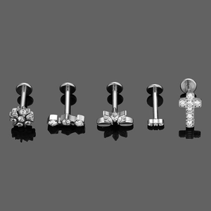Detailed view of silver G23 titanium labret studs with zirconia floral and cross designs