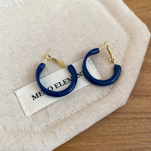 Close-up of minimalist dark blue enamel C-shape hoop earrings with gold-tone metal posts