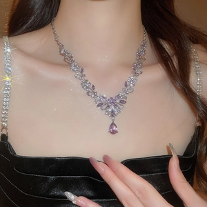 Close-up of model wearing an elegant silver necklace with purple teardrop gems and crystals