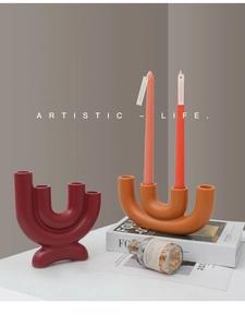 Close-up of modern U-shaped matte ceramic candle holders in dark red and orange colors