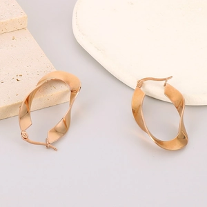 French vintage irregular gold wave U-shape titanium earrings on a textured stone display
