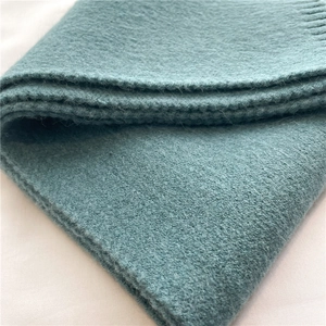 Close-up of soft knitted texture on teal winter scarf with thick wool fibers