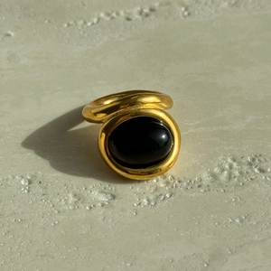 Vintage 18k gold plated titanium ring with oval black stone on stone background