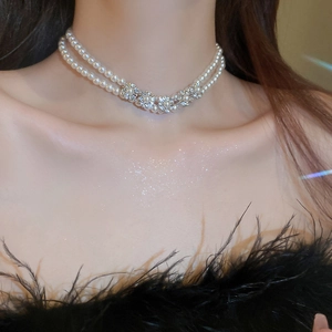 Detail of double-layer pearl necklace featuring diamond-studded flowers on model neck