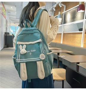 Detail view of a green school backpack with cute bunny ears and a plush rabbit pendant