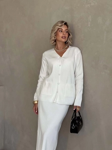 Detail of white knit two-piece set showing ribbed texture and elegant cardigan pockets