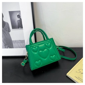Gros plan sur le motif cœur gaufré vert et les détails dorés du petit sac à main