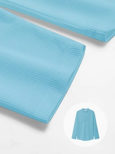 Macro texture of sky blue waffle fabric on a long sleeve men's polo shirt with buttons
