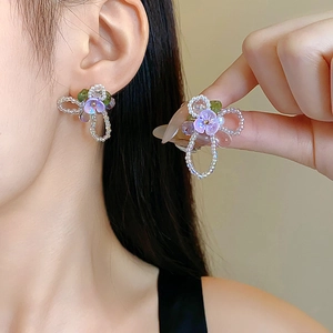 Handmade purple flower tassel earrings with green and clear crystal beads on a model