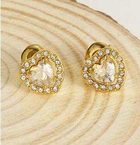 Macro shot of double-layer gold heart stud earrings with cubic zirconia on wood background
