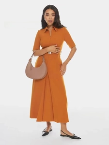 Detail of a chic apricot crescent handbag styled with a trendy orange midi shirt dress
