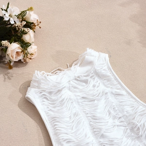 Dettaglio del top bianco con frange traforate e decorazione di petali di rosa