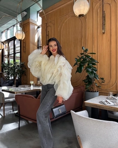 Détail de l'élégante blouse en organza beige avec manches à volants multicouches