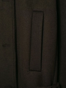 Macro detail of dark brown wool fabric texture and side pocket on cropped jacket