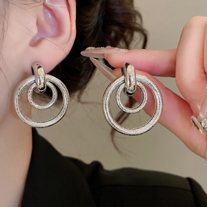 Détail de boucles d'oreilles double créoles argentées avec fini martelé poli