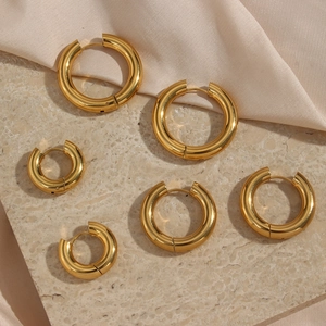 Thick 18K gold plated stainless steel hoop earrings in three sizes on silk background