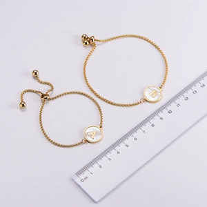 Detail of adjustable 18k gold plated bracelets with A and B shell letter pendants